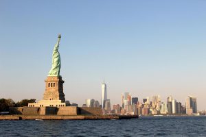 Statue of Liberty in foreground along Hudson River with view of Lower Manhattan in background