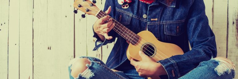 This is a shot of a torso in a denim outfit and playing the guitar.
