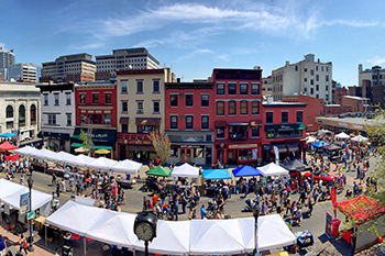 Photo of the Hoboken Art and Music Festival with crowded street lined with tents and an overview of the brownstone buildings that line the street.