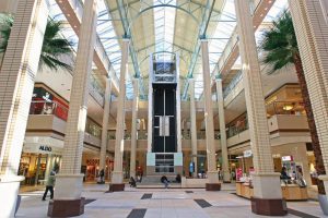 Interior shot of the Newport Mall Plaza with fake palms and sky lights. The grand halls show the three stories are exposed on both sides.