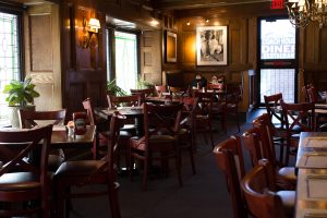 Interior shot of a diner in hudson county that has wood chairs and tables with menus and place seatings at each.