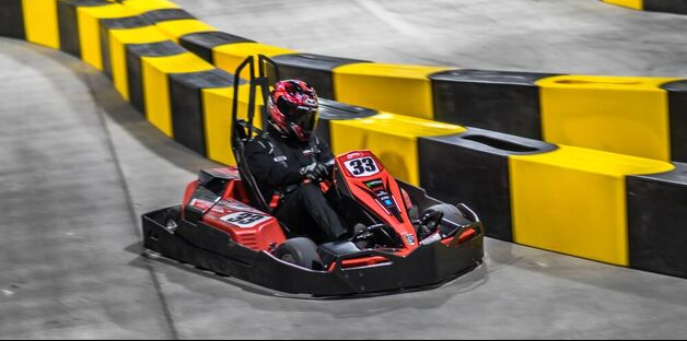 photo of person wearing a motorcycle helmet on a go cart going down a track