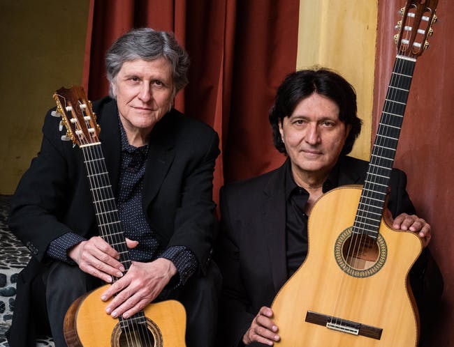 Two men, Strunz and Farah, holding guitars