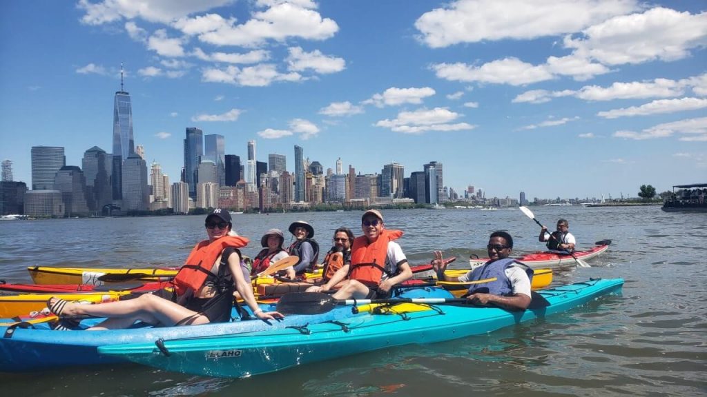 group of people kayaking on the river with the Manhattan skyline in the background