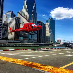 red helicopter taking off from helipad 