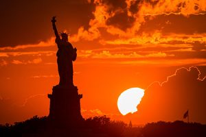 photo of the silhouette of the Statue of Liberty against a sunset
