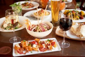 Various plates of food and two glasses of wine 