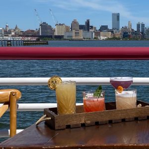 Three cocktails on a table with a waterfront view