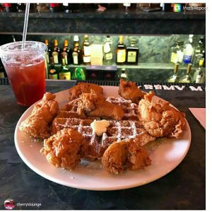 Plate of Chicken and waffles and a cup of iced tea on the side