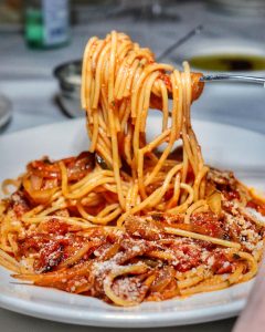 fork lifting spaghetti from a plate of spaghetti and tomato sauce