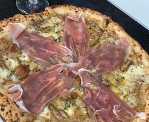 Pizza pie with prosciutto topping