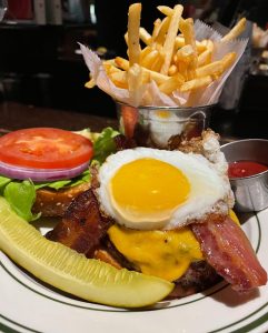 Bacon cheeseburger burger with an egg with a side of fries