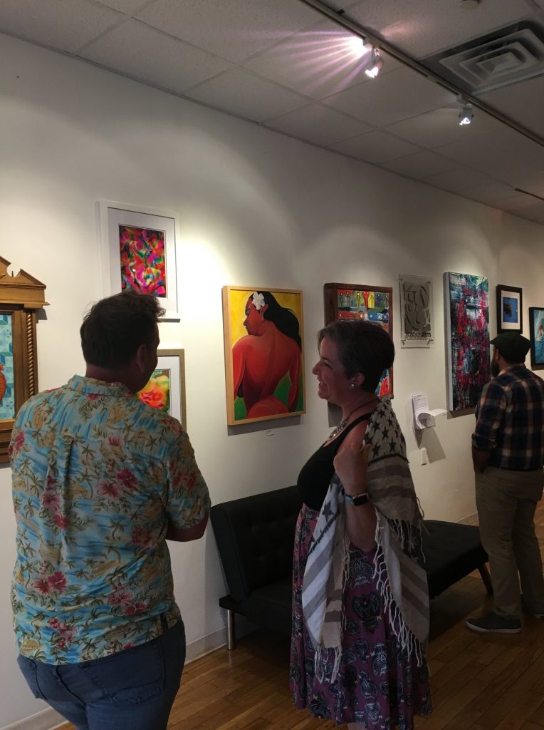 Hoboken Arts art gallery event, man and woman talking in front of gallery wall of art