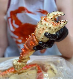 gloved hand holding the claw of a king crab