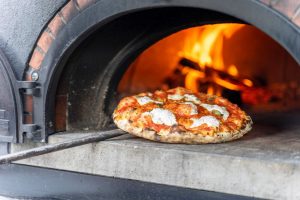 pizza pie being placed in wood fired oven at smorgasbar