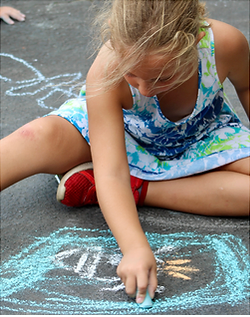 girl drawing with chalk on pavement