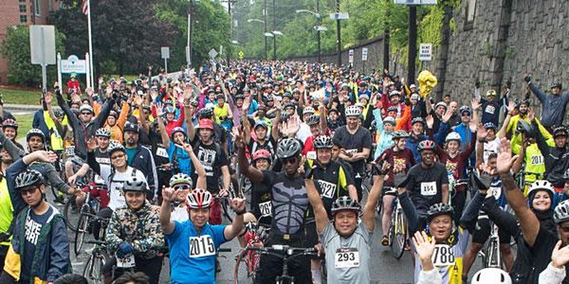 Large crowd of cyclists most cheering with hands up