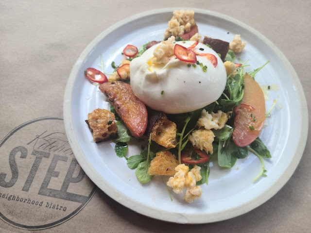 An image of a beautiful dish from Kitchen Step restaurant in Hudson County, featuring fresh greens and a poached egg.