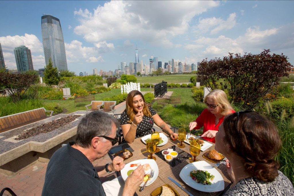 group dining outdoors at restaurant overlooking Manhattan skyline