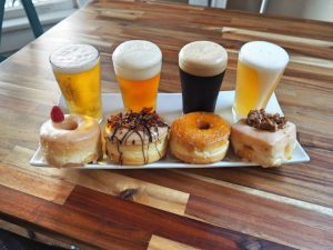 row of 4 glasses of beer with 4 donuts