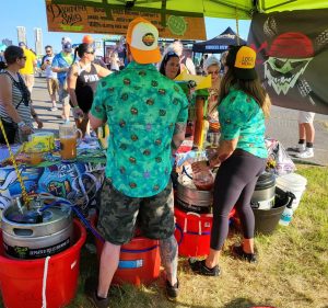 2 people in matching green shirts and caps selling beer at an event 