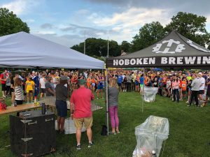 large crowd of people and two tents, one has "Hoboken Brewing" on it with their logo