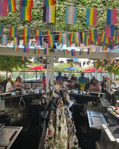 Outdoor bar with rainbow flag buntings stringed up over the bar