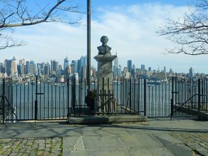 statue of bust on a pedestal with city skyline in the background