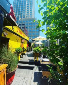 Outdoor dining area on a sunny day outside yellow bar called 'Iron Monkey"