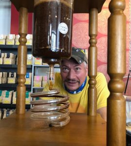 man watching coffee brew and drip through a spiral tube