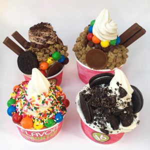 4 cups of frozen yogurt with various candy and chocolate toppings