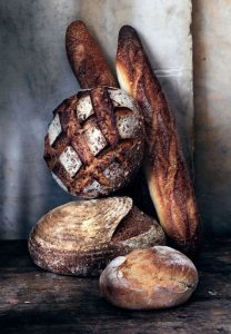 Various types of bread arranged for photo; Long breads, sourdough boules, etc.