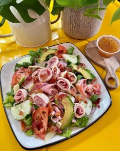 salad on a white square plate on a yellow table