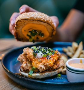 hand placing bun on a fried chicken sandwich