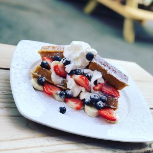 plate of waffle with whipped cream and strawberries and blueberries