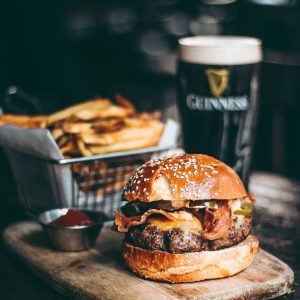 glass of Guinness beer with a burger and fries