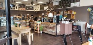 Inside Park Cafe, counter with employee at register with coffee, pastries and other assorted to-go food behind glass