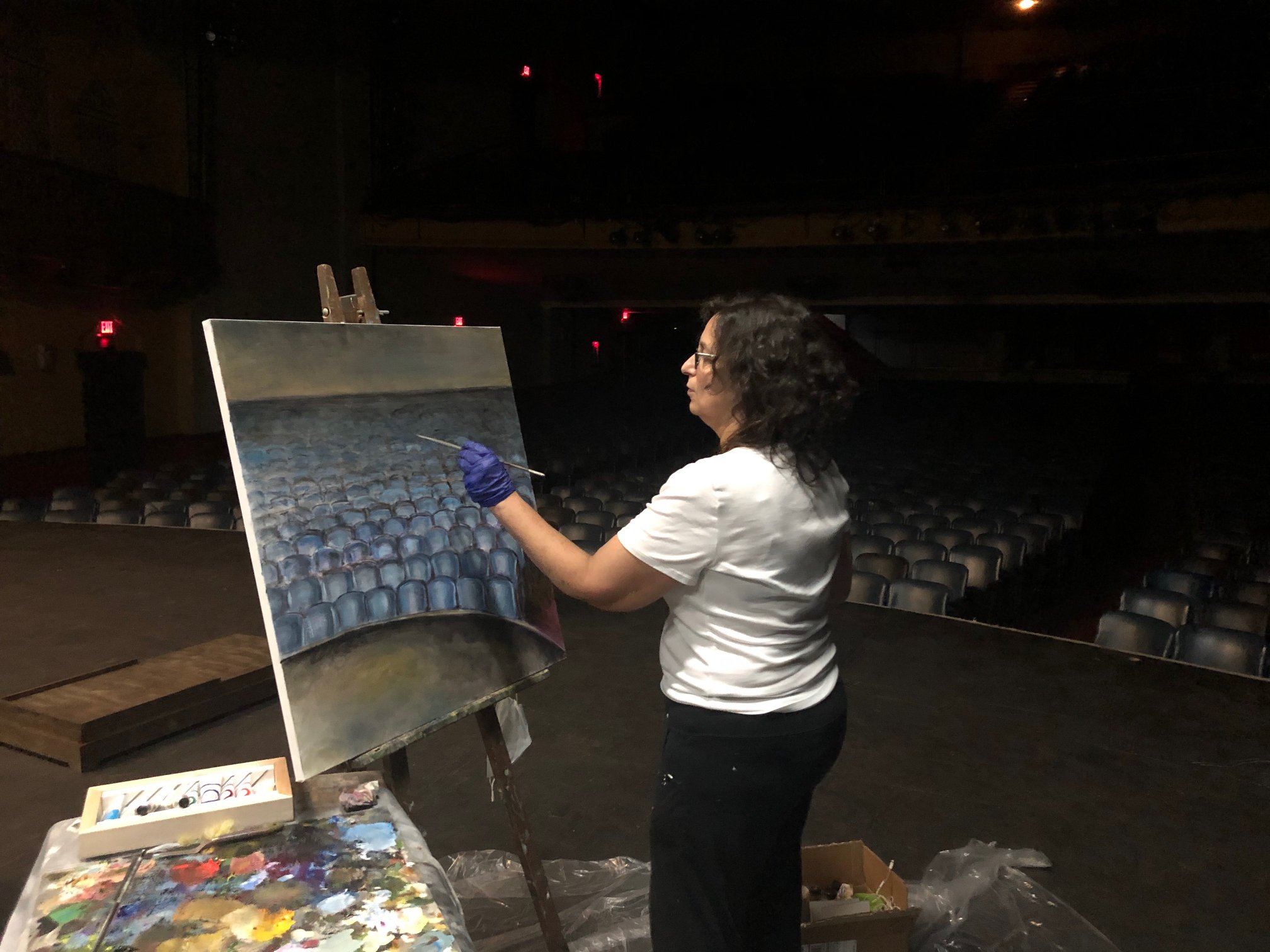 woman painting on a canvas on a theater stage