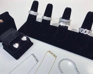 silver rings on a black jewelry holder as well as 3 necklaces 