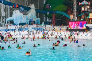 DreamWorks Water Park in American Dream, dozens of people in a large pool surrounded by large water rides