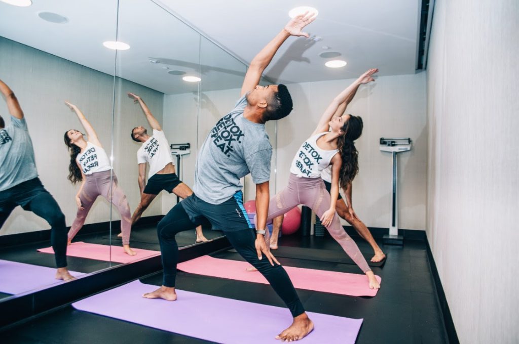 Image of people stretching on mats in front of a mirror for a workout class