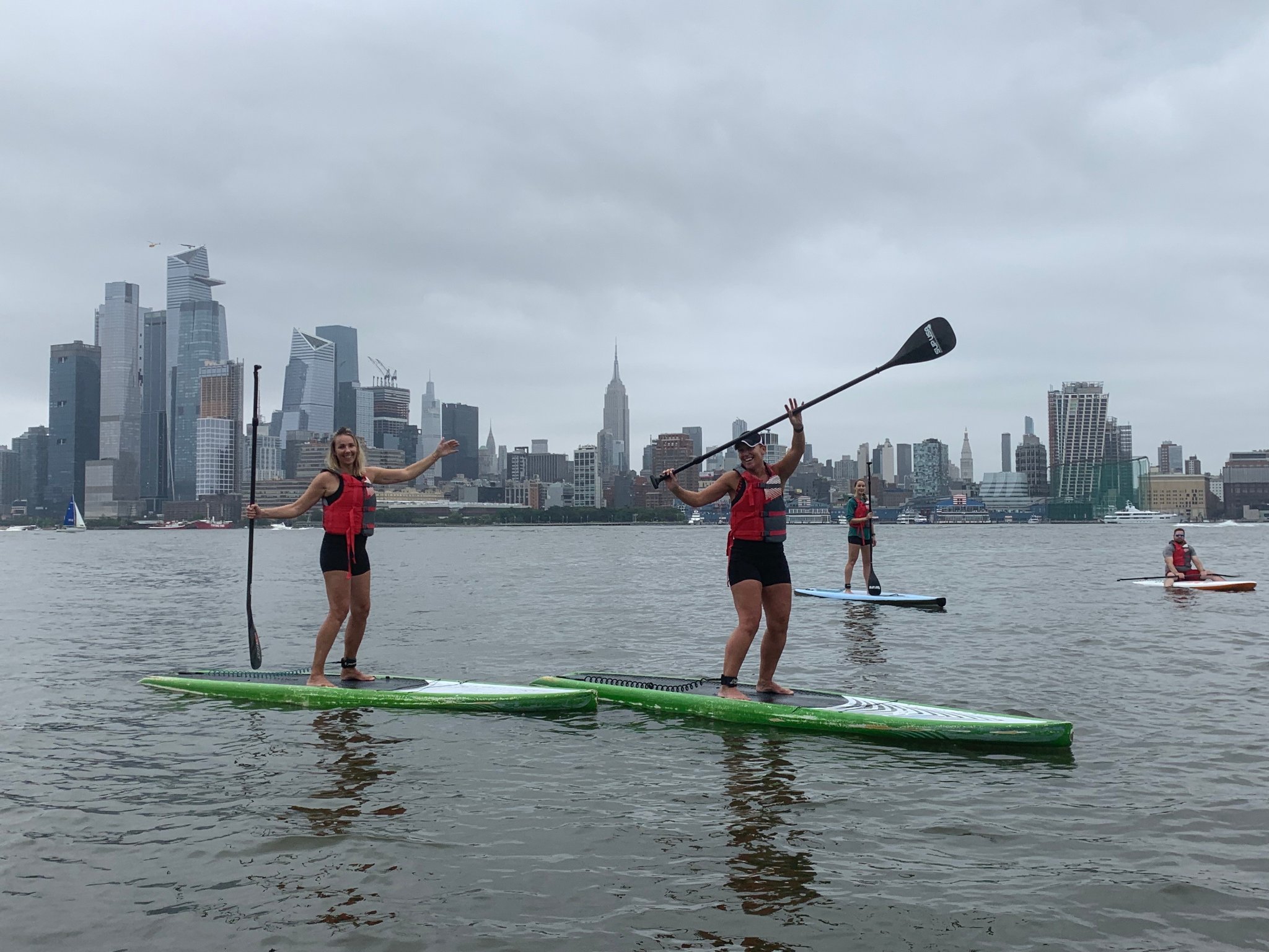 group paddle boarding on the Hudson River with the new york skyline in the background